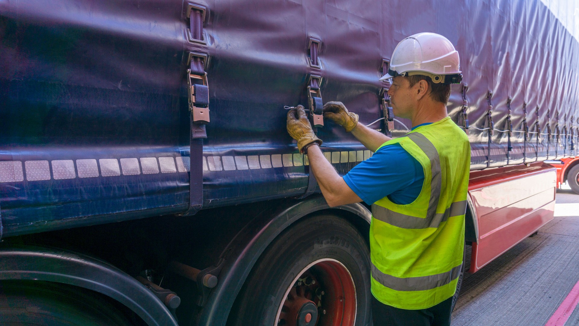 Driver Wearing Protective Clothing fastening up TIR Cables through the Buckles